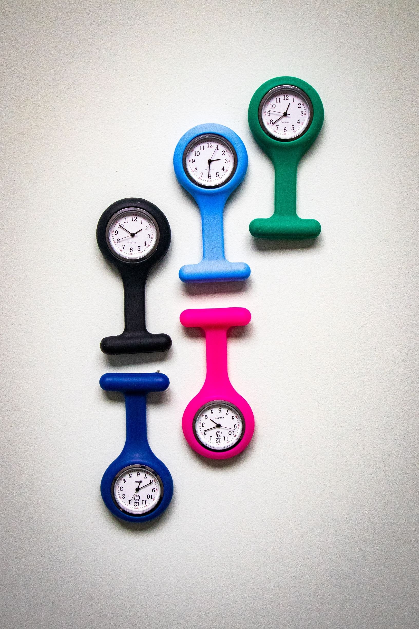 RMIT Store fob watches in black, light blue, teal, navy, and magenta, neatly aligned on a white background with three at the top and two at the bottom. Each watch features a silicone casing and a white round face with black hour, minute, and second hands.